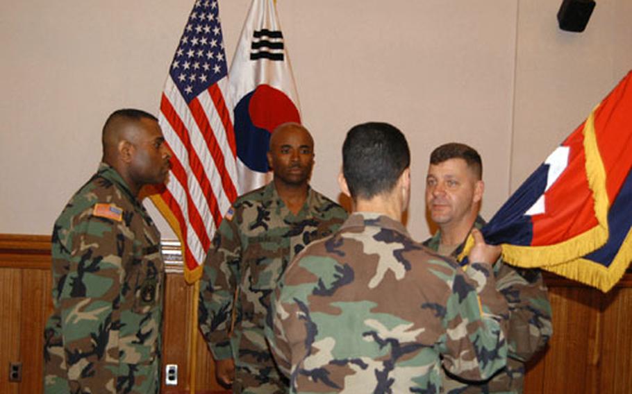 Command Sgt. Maj. Joseph Zettlemoyer (right) hands over 2nd ID&#39;s 1st Brigade colors to his commander, Col. Anthony Ierardi, while new 1st Brigade Command Sgt. Maj James Williams Jr (left) prepares to recieve them.