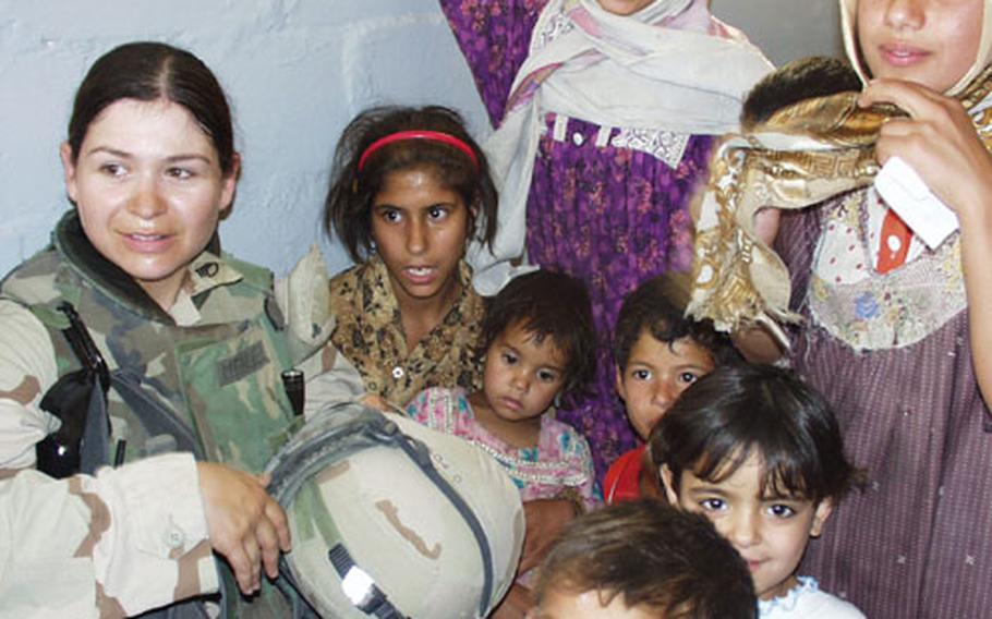 Staff Sgt. Heidi Mendez of Miami and the 478th Civil Affairs Battalion gets swarmed by local children Thursday during a medical outreach visit to Al-Rashad, a village on the northeastern edge of Baghdad.