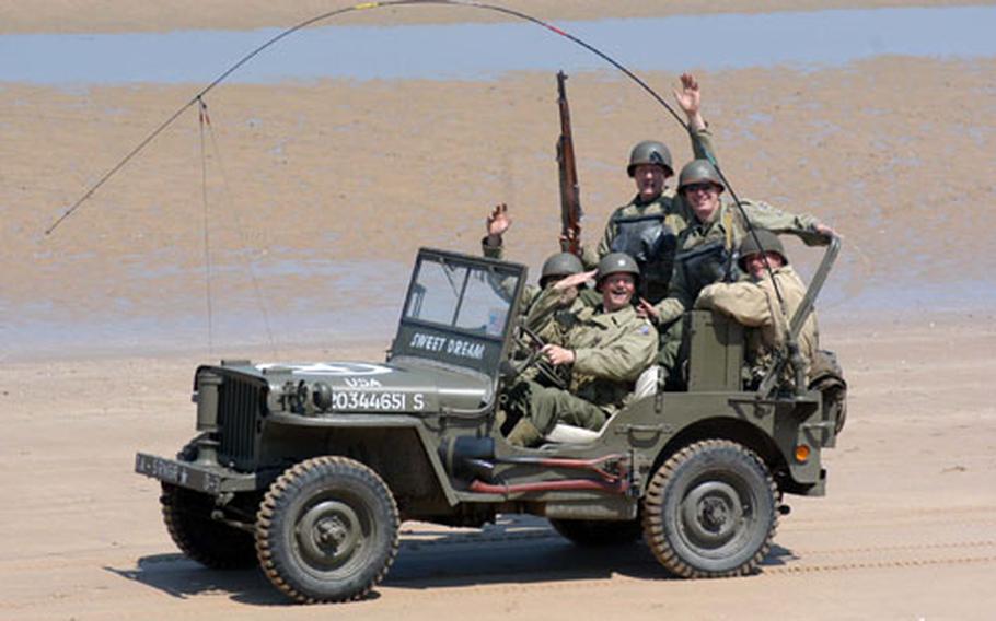 Military enthusiasts salute and wave to spectators as they drive along Omaha Beach in a World War II vintage jeep. Fans of World War II memorabilia gathered at Normandy this week for the 60th anniversary of D-Day.