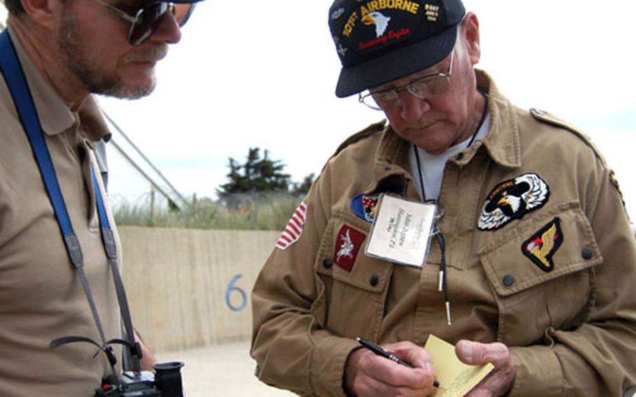 John Agnew, right, a 101st Airborne Division veteran, signs an autograph at Utah Beach, France, on Friday. Thousands of veterans have come to the beaches of Normandy fot the anniversary of the D-Day invasion.