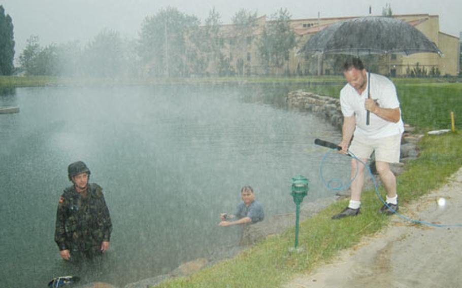 At Camp Walker Golf Course in Taegu, South Korea, Army Col. James M. "Mike" Joyner, left, tapes a TV spot with safety tips for Korea&#39;s monsoon season. Joyner is commander of Area IV Support Activity in Taegu. At right, in water, is his public affairs chief, Kevin B. Jackson. Holding umbrella is Willie DeCook, the unit&#39;s director of resource management.