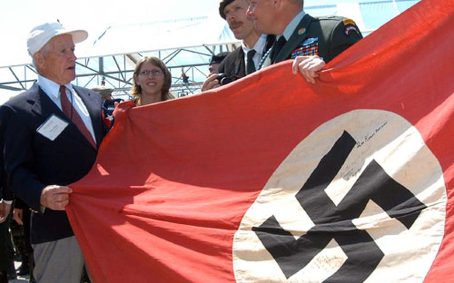 Ivor Jones, left, a 2nd U.S. Ranger Battalion veteran, holds a Nazi flag captured at Pointe du Hoc, as he talks to Rangers and visitors to the 60 anniversary of D-Day ceremony there on Sunday.