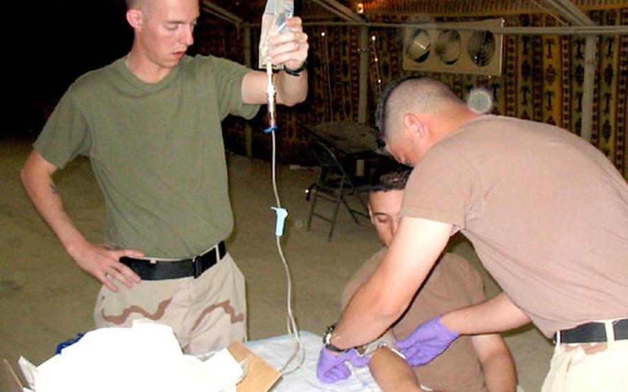 Petty Officer 2nd Class Jason Williams, left, a corpsman with 2nd Medical Battalion&#39;s Company A, holds an intravenous bag while a Combat Lifesaver student tapes down the IV on a fellow student&#39;s arm during a recent class at Camp Virginia, Kuwait.