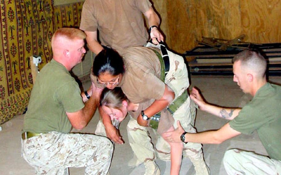 Petty Officers 2nd Class Terry Sitton, left, and Jason Williams, right, teach Combat Lifesaver students how to carry someone injured in combat during a recent class at Camp Virginia, Kuwait. Both Sitton and Williams are corpsmen assigned to the 2nd Medical Battalion&#39;s Company A.