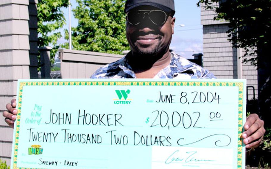 John Hooker, a civilian with the Army Materiel Command, holds up his winning check from the Washington state lottery.