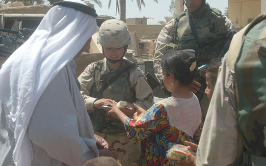 Spc. Maria Torres, of the 81st Brigade Combat Team, a National Guard civil affairs team from Seattle, distributes combs and soap to women of the Temimi tribe during a mission Monday to build better relations with the community outside of LSA Anaconda, Iraq.