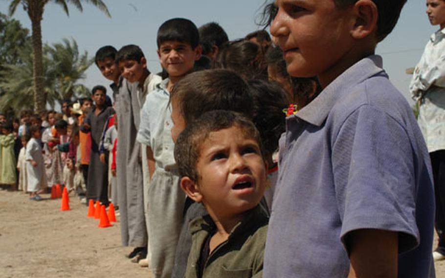 Iraqi children within the Al Fadouz village near Balad, Iraq, wait in line Monday to receive toys, T-shirts, shoes and hygiene products from civil affairs soldiers from LSA Anaconda. Future civil affairs missions include providing poor villages with drinkable water and water for washing with. Many of the communities do not have clean water and use water from canals off the Tigris River.