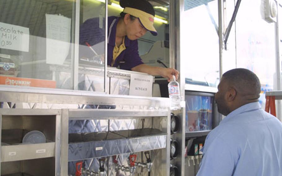 Masako Suda, operator of the Naval Air Facility Atsugi’s Navy Exchange Mobile Canteen, hands a bottle of water to Petty Officer 2nd Class Kevin Phillips, from the Aircraft Intermediate Maintenance Department, Atsugi. The Mobile Canteen travels around Atsugi offering a variety of meals and snacks to the base community.