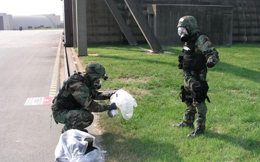 Explosive Ordnance Disposal troops at Osan Air Base, South Korea, practice coping with mock enemy chemical devices. The training was part of a weeklong U.S. Air Force combat readiness exercise in South Korea. At left is Airman 1st Class Nathan Lund, wrapping the chemical device in plastic. At right is Senior Airman Michael Fink. Both are with the Explosive Ordnance Disposal Flight of the 51st Engineer Squadron, part of Osan&#39;s 51st Fighter Wing.