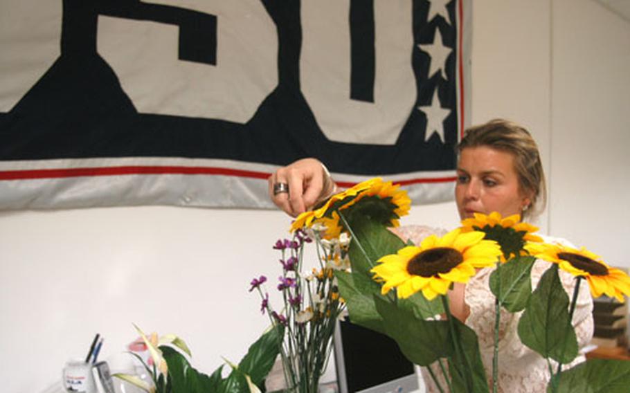 Simona Keeler, acting director of the United Service Organizations in Naples and Rome, arranges flowers for the new office at the Gricignano support site Thursday.