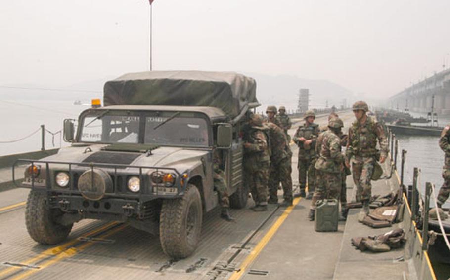 Soldiers from 2nd ID&#39;s 50th Engineers Company climb out of a vehicle after taking one of the first trips across a floating bridge they built over the Han River on Thursday.