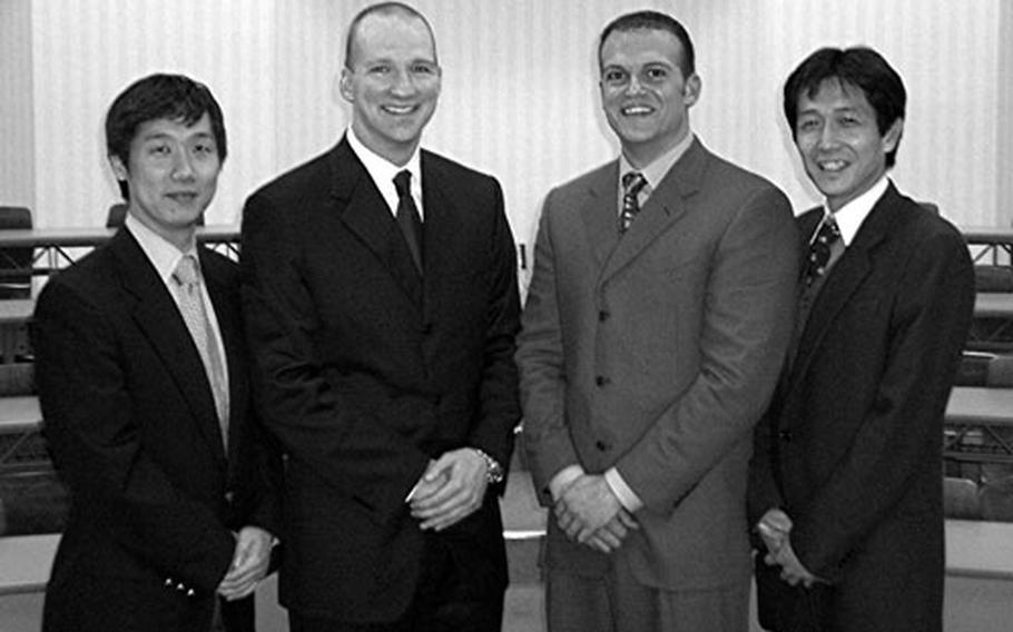 Navy Lt. Cmdrs. Paul Hladon, center left, and Andrew Schiemel, center right, stand with the translators for their book&#39;s "Language and Philosophy of Western Medicine," publicity photo. The translators are Masayuki Yoshida, left, and Tomohiro Morio. All four are physicians.