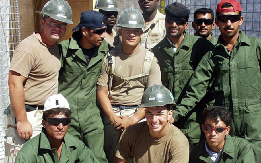 Members of Naval Mobile Construction Battalion 74, in hardhats, pose with some of the Iraqi men whom they are teaching construction skills. The Seabees are, front row, Seaman Apprentice Paul Larson of Corpus Christi, Texas; second row from left, Petty Officer 2nd Class Jeff Boutot of Augusta, Maine, and Petty Officer 3rd Class Carlos Hernandez of Albuquerque, N.M.; third row from left, Petty Officer 2nd Class Chad Robinson of New Orleans and Petty Officer 3rd Class Ishmael Fleming of Natchez, Miss.
