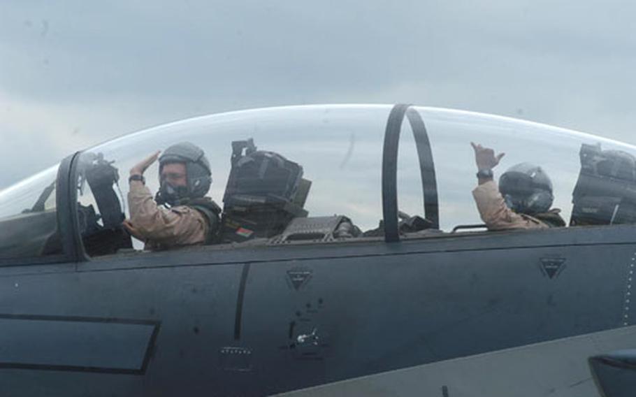 A pilot and weapons systems operator aboard an F-15E Strike Eagle wave to family members and squadron mates Wednesday afternoon on their return to RAF Lakenheath, England.