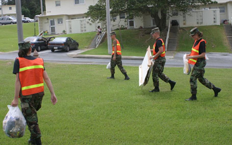 In expectation of high winds and rain from Super Typhoon Dianmu on Okinawa, (Left to right) Airman 1st Class Kristi Stomberg, Airman 1st Class Anthony Dentice, Airman 1st Class James Bark and Airman Stephanie Sinclair of Kadena Air Base collect trash, debris metal and wooden objects that could become projectiles during the storm.