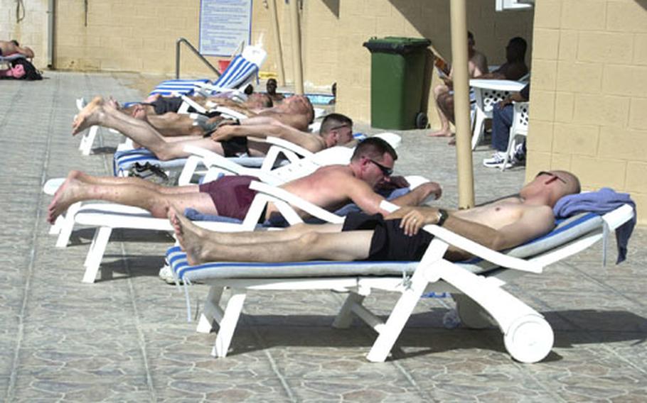 Servicemembers catch some rays while enjoying their four days of rest and recuperation on Camp As Sayliyah, Qatar. The pool is one of the more popular spots for those participating in the Fighter Management Pass Program.