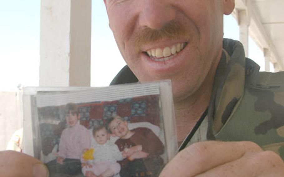 Staff Sgt. Chuck Campbell, of Center Harbor, N.H., holds up a photo of his kids, Ian, Rachael and Alicia.