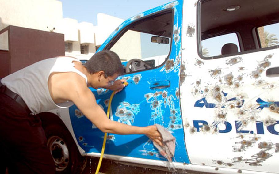 An Iraqi policeman washes a patrol truck that insurgents riddled with AK-47 rounds.