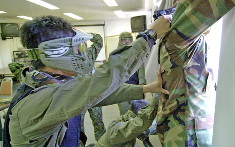 Terrorist role players force their hostages to shout demands out a window during a anti-terrorism exercise at Camp Zama.