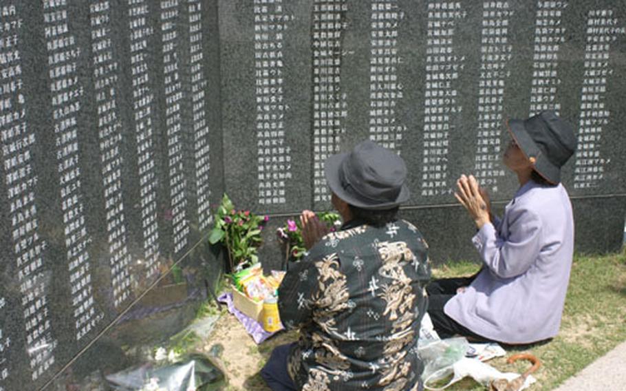 Relatives of deceased family members hold prayers at cenotaphs in the Cornerstone of Peace area at the Okinawa Peace Memorial Park in Itoman on Wednesday before a ceremony commemorating the Battle of Okinawa. More than 236,000 names of the men and women who lost their lives in that battle are inscribed on the walls.