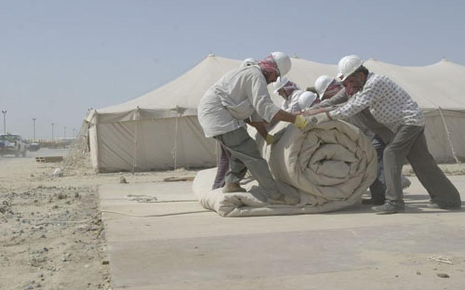 Local Kuwaiti workers roll up a tent. Camp Wolverine, which was the Aerial Port of Debarkation, is set to close in several weeks. All APOD operations have already moved to Camp Doha, Kuwait.