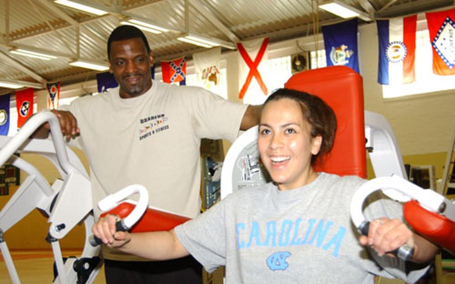 Mark Lewis, Kelley Barracks Fitness Center facility manager, looks on while Pfc. Nancy Coronado tries out some Nautilus equipment Saturday at Cambrai-Fritsch Fitness Center. Coronado was one of 22 women who took the women&#39;s weight resistance training course, a new program offered at all fitness centers in the 26th Area Support Group.