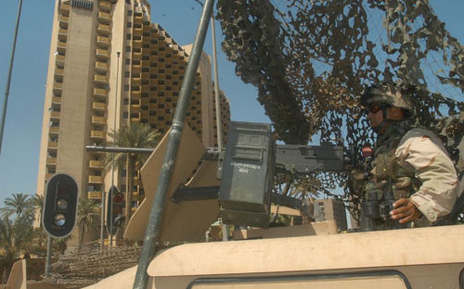 Spc. Moises Becerra of Eugene, Ore., and Company C, 2nd Battalion, 162nd Infantry Regiment, keeps watch Monday from inside his turret atop a Humvee outside of the Palestine Hotel in downtown Baghdad. Monday&#39;s handover of power to the new Iraqi government caused soldiers outside the hotel to be on high alert.