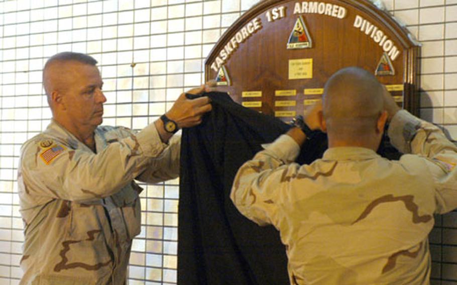 Command Sgt. Maj. Michael Bush, left, the 1st Armored Division command sergeant major, and Spc. Romulo Escobedo unveil a plaque honoring members of 1st AD task force killed in Iraq during a ceremony at Freedom Rest Sunday. Nearly 100 names are engraved on the plaque, about 40 of which died after the April extension of the division.