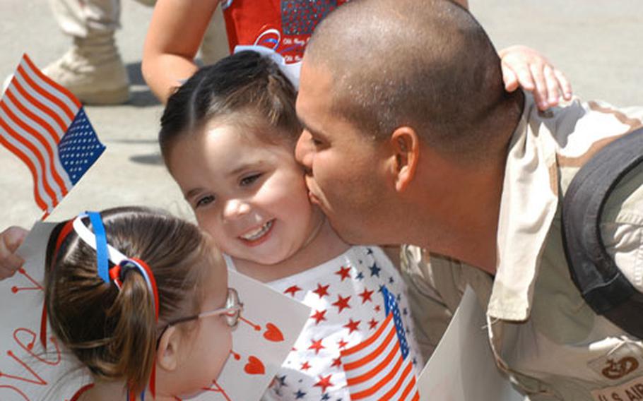 Staff Sgt. Ramiro Rodriguez kisses daughter Lillie, 2, as Emilee, 1, watches at Misawa Air Base, Japan. More than 70 servicemembers, most of whom are with Misawa&#39;s 35th Civil Engineer Squadron, returned from a three-month deployment in Iraq on a flight charted by Air Mobility Command.