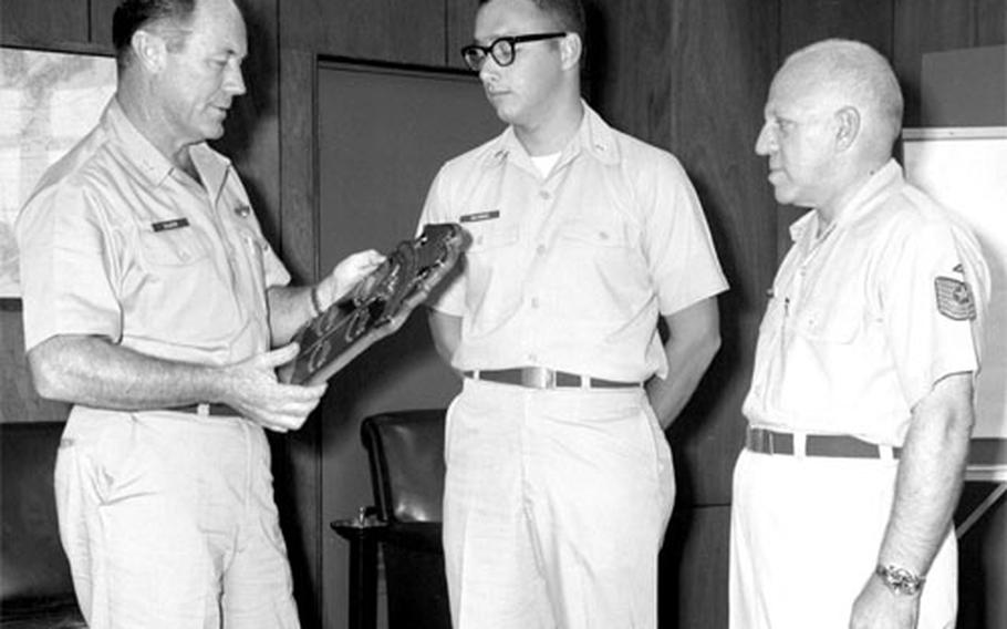 On a more down-to-earth matter, Col. Chuck Yeager presents a plaque for outstanding performance to 2nd Lt. Thomas Holycross, center, and MSgt. Richard M. Rochlin, right.