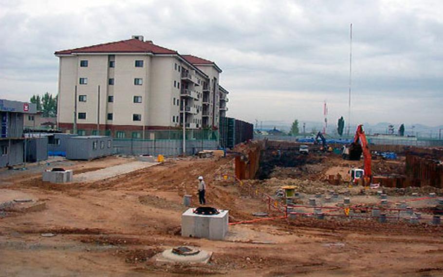 Workers digging at the site of a family housing complex going up at Camp Humphreys, a U.S. Army helicopter base in Pyongtaek, South Korea. Families last September moved into the building at left, the first of three that will eventually stand at the site.