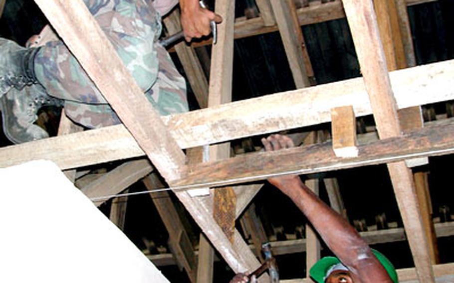 Petty Officer 3rd Class Jacob Byrne, left, of Naval Mobile Construction Battalion 74, and Cpl. Kpeli Victor, of the Ghanaian 49th Engineer Battalion, work on the ceiling at the Haatso Medical Clinic near Accra, Ghana, earlier this year. The Haatso Medical Clinic, completed in June, provides services to underprivileged women and children in Ghana. Since January, Battalion 74 sailors and officers worked on projects in western Iraq, Sicily, Crete, Ghana and Croatia, as well as Rota.