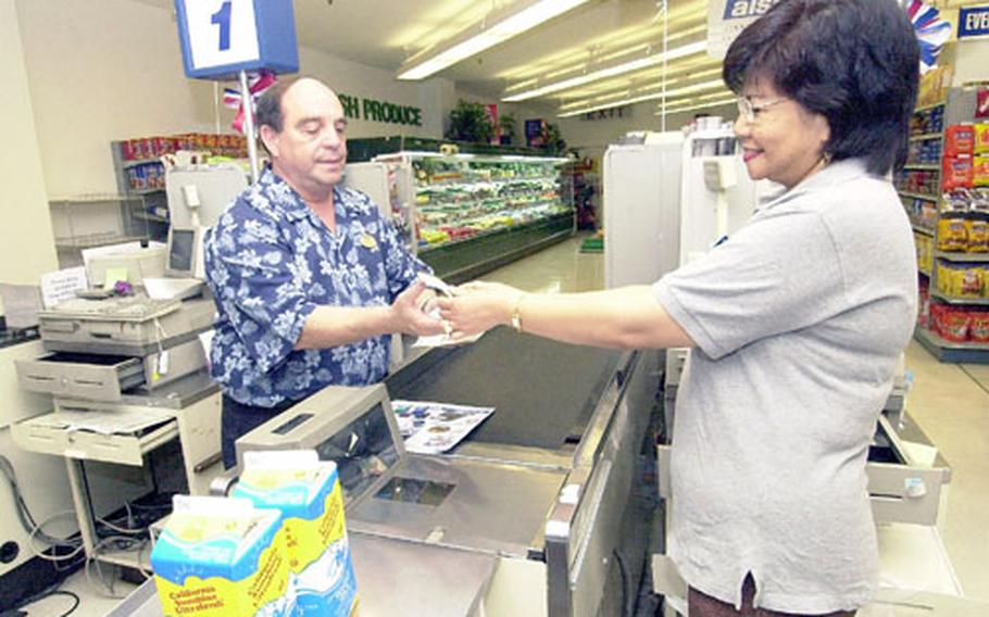 Fred Garcia, general manager of the Negishi Club, accepts change from cashier Helen Narita at the Negishi Exchange. The exchange was awarded the Bingham Award for 2003.