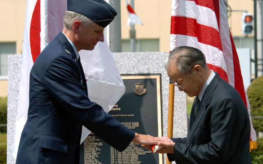 Col Mark Schissler, at left, commander of the 374th Air Wing at Yokota Air Base returns a Japanese flag to Manshichi Saeki during a ceremony in front of the headquarters building. The flag belongs to Ippei Saeki, younger brother of Manshichi, who died fighting against American forces during World War II almost 60 years ago.