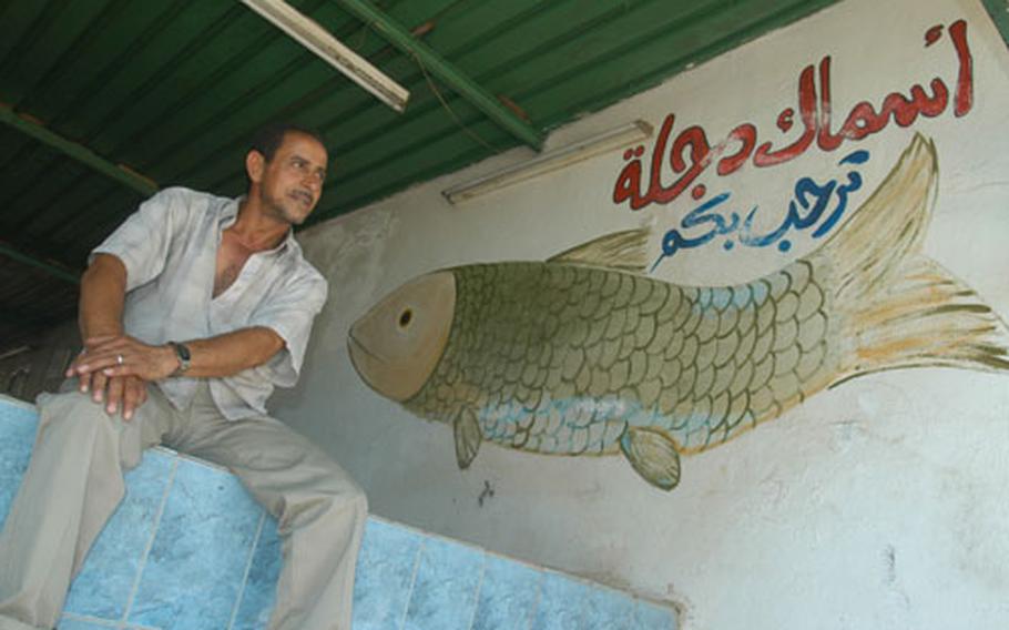 Muhan Hassan Mizaal al-Saadi sits in the doorway of his grilled fish restaurant Friday. Behind the restaurant, Army engineers are in the second phase of a project to renovate and re-open a large park on the east bank of the Tigris Restaurant in Baghdad&#39;s Rusafa neighborhood. Al-Saadi hopes that the park will bring people back to the park, and consequently, his restaurant.