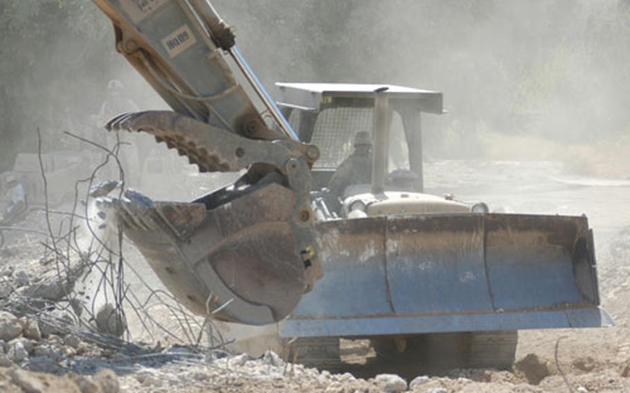 Sgt. Felinar Guillermo watches from his bulldozer as Sgt. George Daoang rips out concrete and rebar from a park fountain in Baghdad&#39;s Rusafa neighborhood. The two, members of the Army Reserve&#39;s 411th Engineer Battalion, are part of the nearly five dozen engineers working on the riverside park, which is expected to reopen to the public in November.