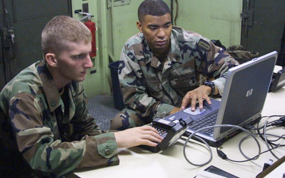 Sgt. Jason Glover, shop foreman with the 1st Signal Brigade, reviews Automated Network Control Device functions with Pfc. Kent Fox, a radio/communications security repair soldier with 307th Signal Battalion, during a class at Camp Carroll during the Warrior Storm II exercise June 27. The exercise was in preparation for Ulchi Focus Lens, a computer war simulation exercise that starts Aug. 23.