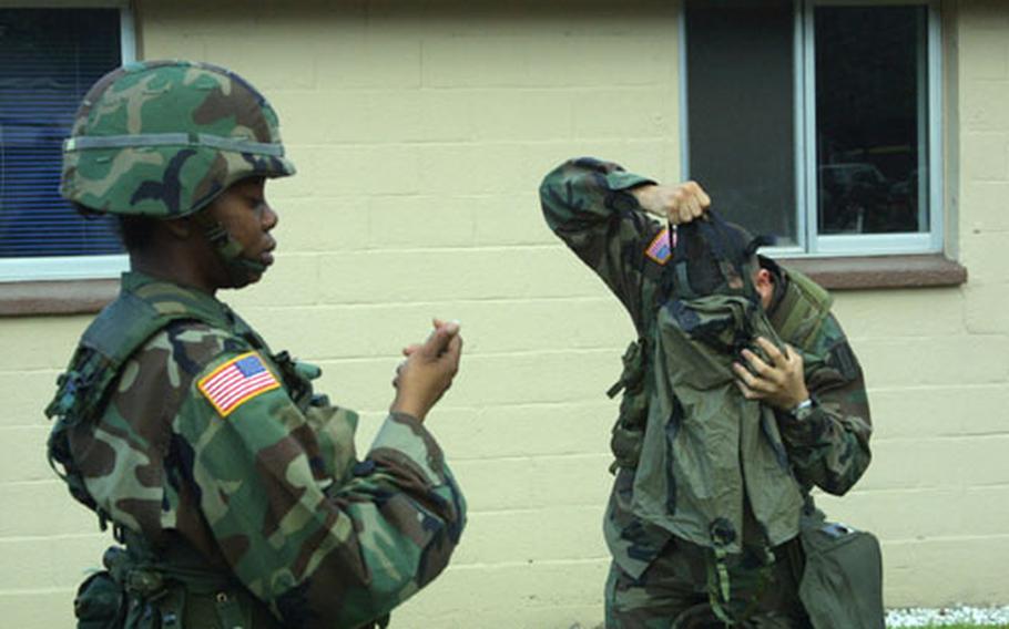 Sgt. Vanessa Taylor times Sgt. Michael Cavezza as he demonstrates donning a protective mask during Nuclear, Biological and Chemical training June 29. Both 1st Signal Brigade soldiers were training as part of the Warrior Storm II exercise, a train-up for Ulchi Focus Lens, a computer war simulation exercise that starts Aug. 23.