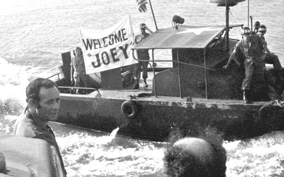 MPs on a river patrol boat displau a banner welcoming Joey Bishop, left.