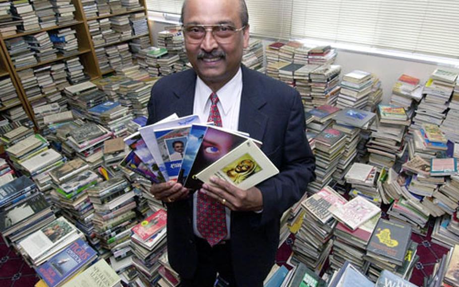 Atsugi Naval Air Facility Library Director Dr. George Marangoly displays the books he has written in his native Indian language.
