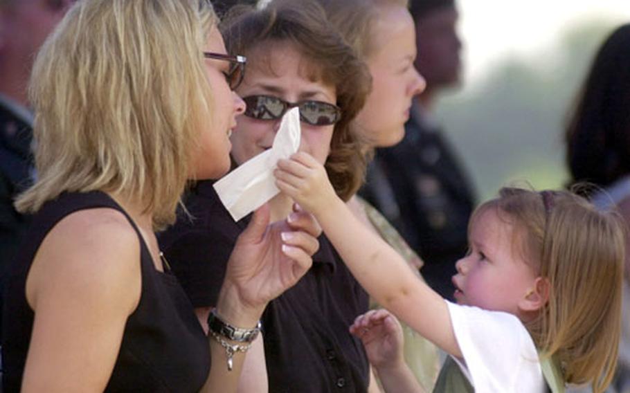 Olivia Snow, the three-year-old daughter of Chief Warrant Officer David Snow, hands a tissue to Brandi Norman, widow of Capt. Kevin M. Norman. The Snow and Norman families attended the dedication of a memorial to Kevin Norman and David Snow, killed one year ago today in a plane crash south of Seoul.