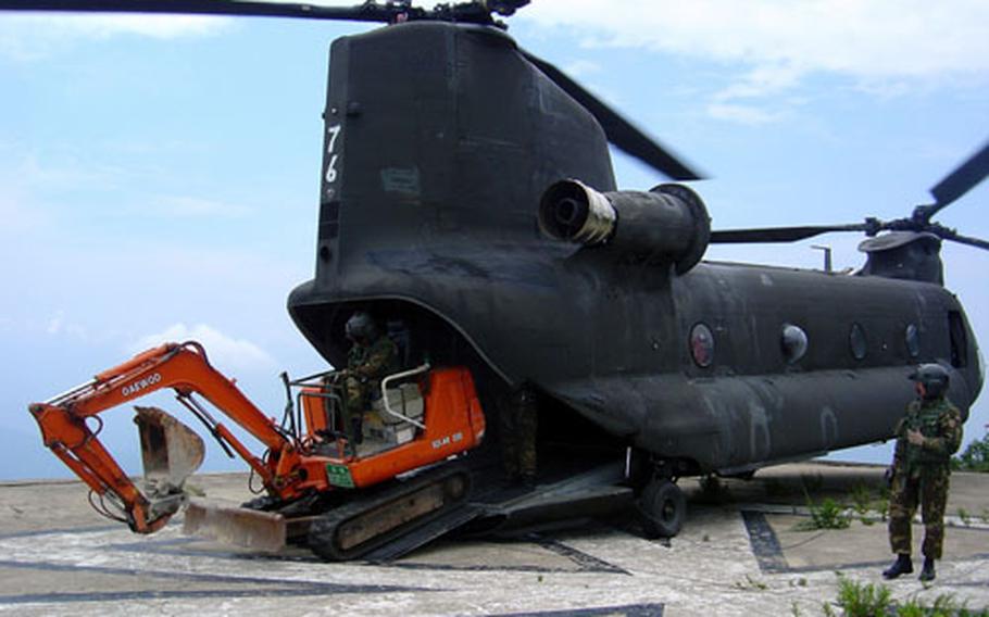 At a U.S. Army radio site on a mountaintop in lower South Korea, a CH-47 Chinook helicopter disgorges an excavator that will be used in demolishing old buildings at the site, about 3 miles west of Kumi City.