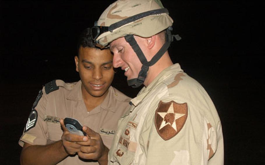 A Kuwaiti police officer shows off a new cell phone to Capt. Andre Takacs, who commands Company A, 1st Battalion, 9th Infantry Regiment. Local police showed 2nd ID soldiers the way during convoys in Kuwait this week.