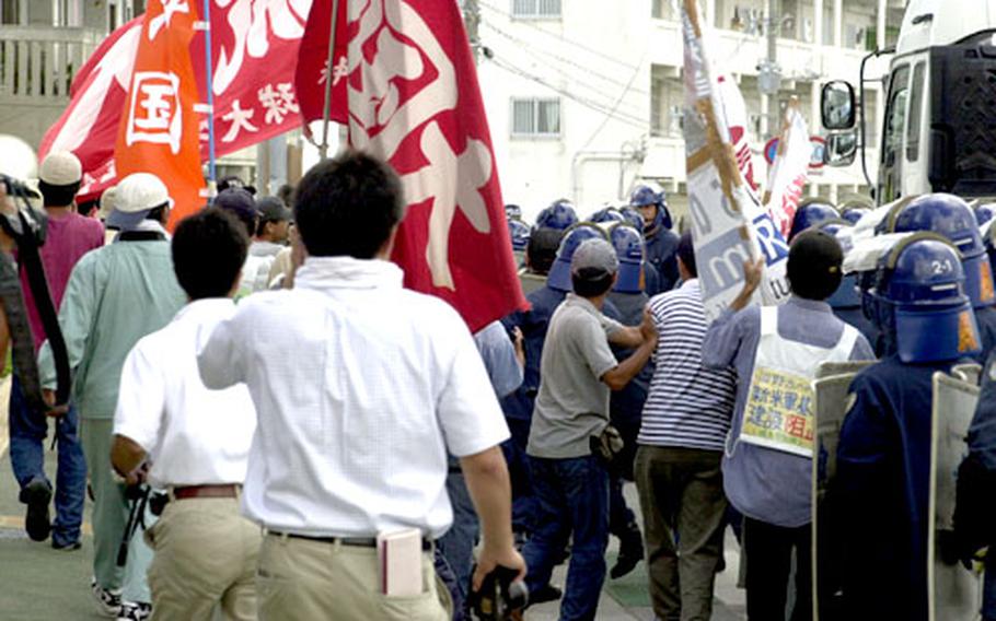 Protestors chase the truck carrying the tail section of the CH-53D. They ventured into the street several times, only to be pushed back by Okinawa riot police.