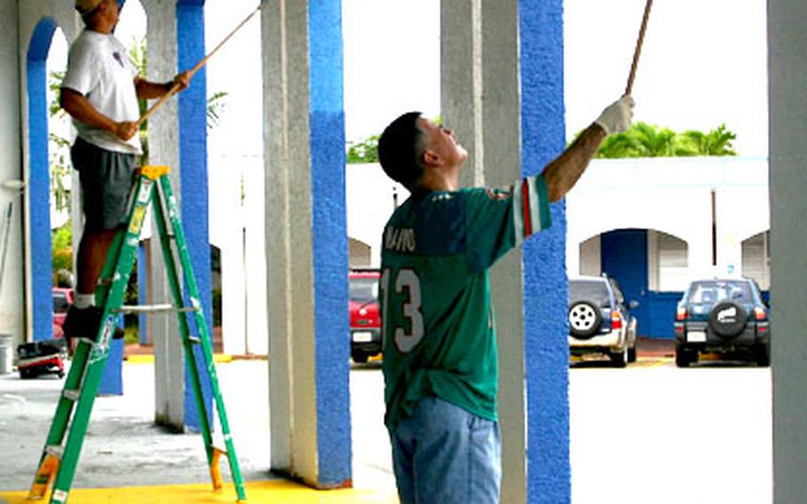 Cmdr. Michael Steinmann, left, and Chief Warrant Officer Steve Taylor of HC-5 paint the walls outside the cafeteria at F.B. Leon Guerrero Middle School.