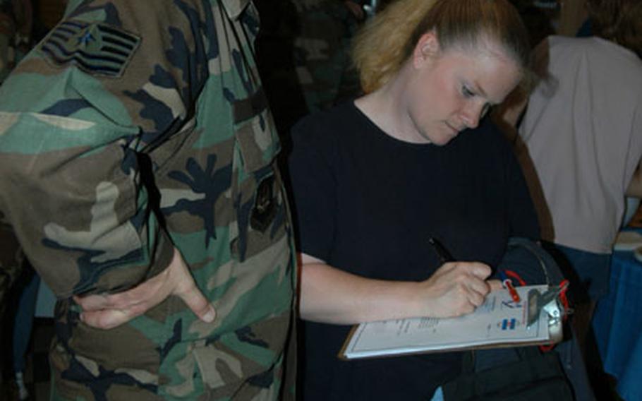 Shari Nance fills out a form so she can stay in touch with other spouses when her husband, Tech. Sgt. Randy Nance, left, goes downrange. Nance, of Spangdahlem&#39;s 606th Air Control Squadron, is deploying in the next AEF rotation.
