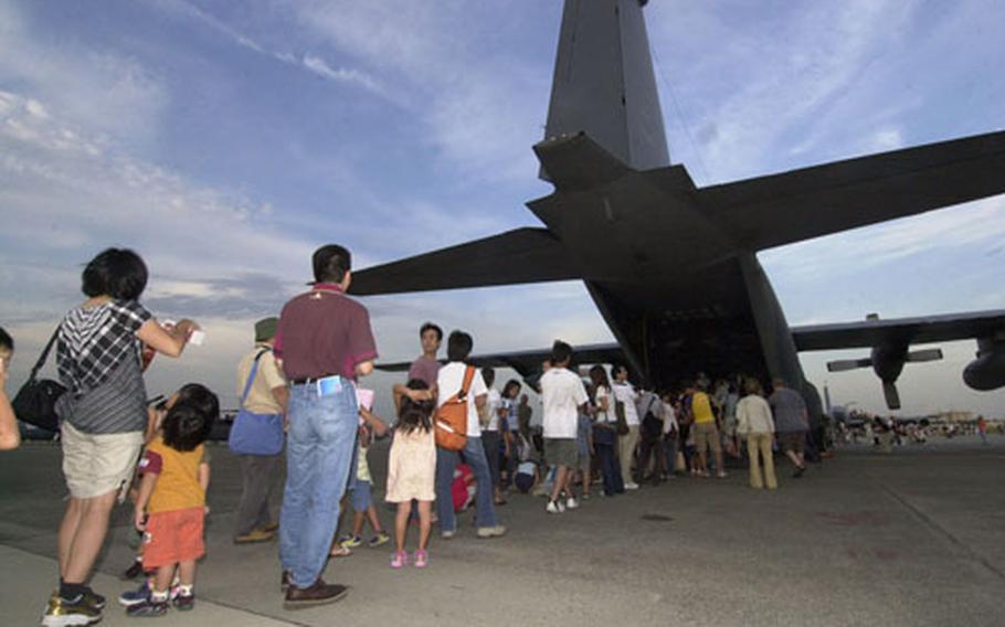Visitors wait in a line to board a C-130 Hercules on display at the Friendship Day Festival at Yokota Air Base.