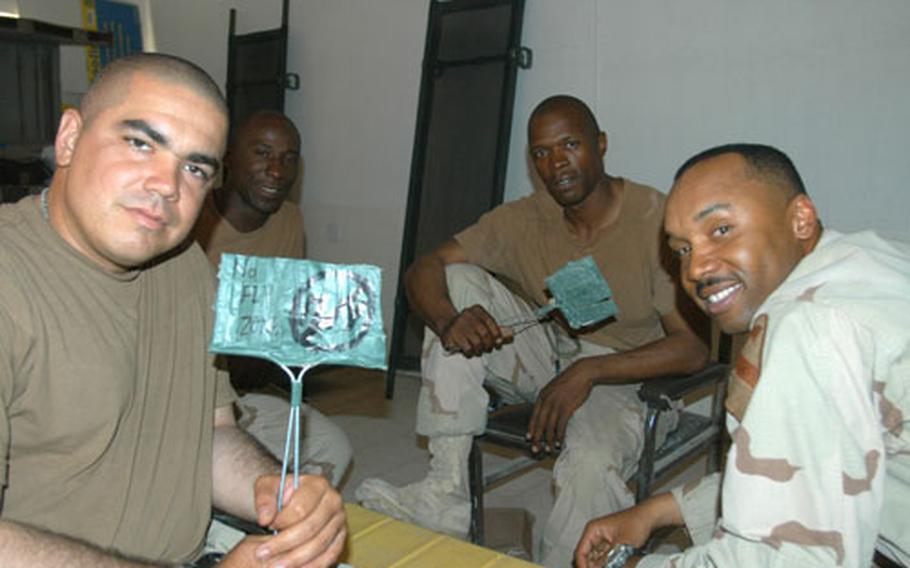 Sgt. Alfredo Garza, left, and Sgt 1st Class John Hopson hold their homemade fly swatters in Najaf, Iraq, between rounds of cards. With them are Spc. Dashea Brown, second from left, and Sgt 1st Class Marlon Anding.