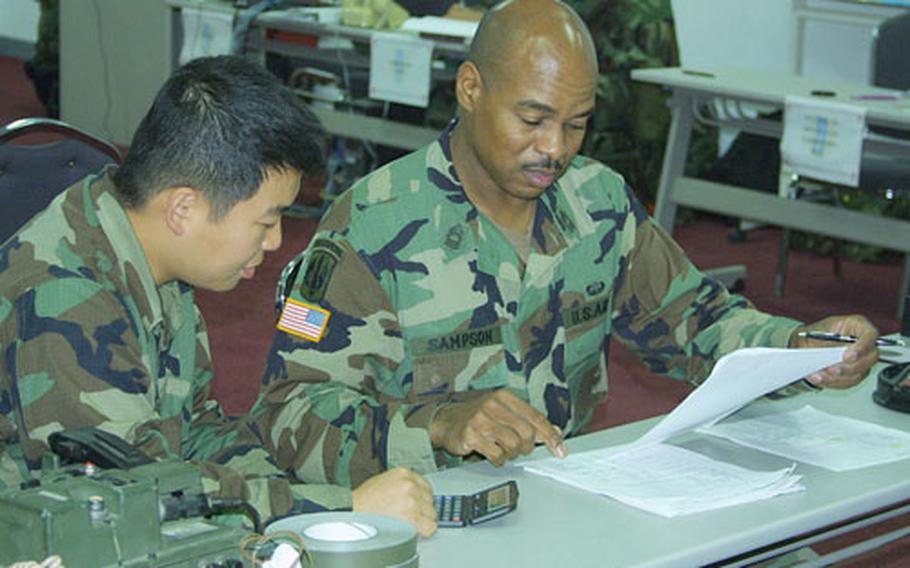 Master Sgt. D.J. Sampson, 1st Signal Brigade food services adviser, and Pfc. Nam Koong-min, the headquarters company nuclear, biological and chemical noncommissioned officer, review logistics reports during the 1st Signal Brigade external evaluation.