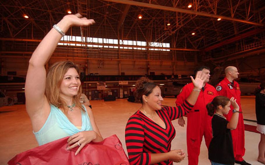 Tamara Maslar, left, and Glenda Deveaux wave to their husbands – Lt. Bobby Maslar and Lt. Napoleon Deveaux - as the sailors return from a five-month deployment.